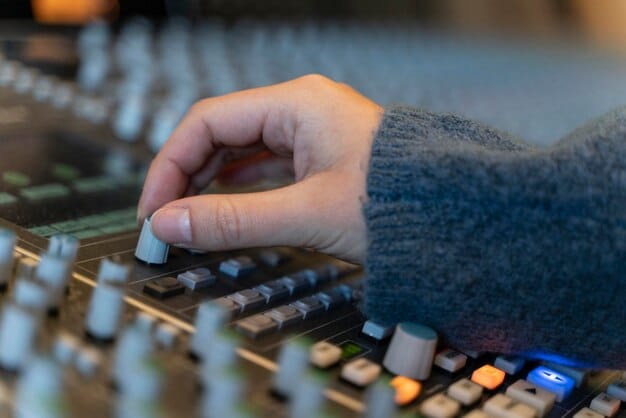 A close-up shot of a music producer's hands working on a digital audio workstation (DAW) with AI-powered plugins visibly assisting in the mixing process. The screen displays complex waveforms and real-time analysis data. The lighting is focused on the hands and the screen.