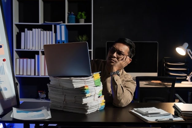 An employee looking stressed at their desk, surrounded by overflowing paperwork and multiple computer screens. The lighting is harsh, and the employee is holding their head in their hands.
