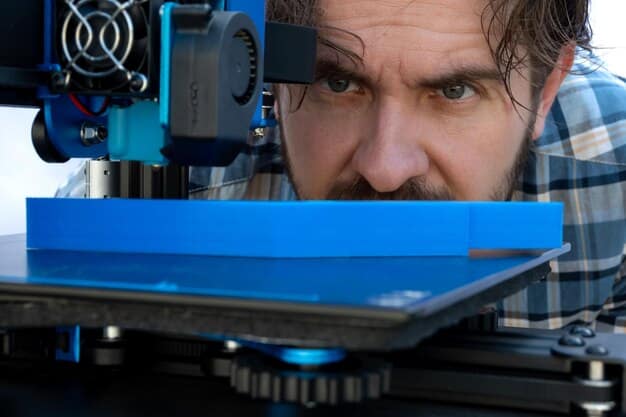 A close-up of a worker using a high-tech 3D printer to create a component at a factory. The focus is on the equipment, with the worker slightly blurred for anonymity. This image represents the technological advancements in manufacturing that the Infrastructure Bill could promote.