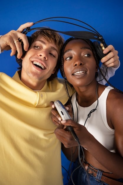 A diverse group of young people, each wearing headphones, smiling and interacting with their phones, illustrating the widespread and personal nature of pop music consumption via streaming.