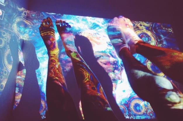 A concert venue filled with a diverse crowd, hands raised, with a large screen displaying empowering messages and artistic representations of social justice symbols, showcasing collective energy.