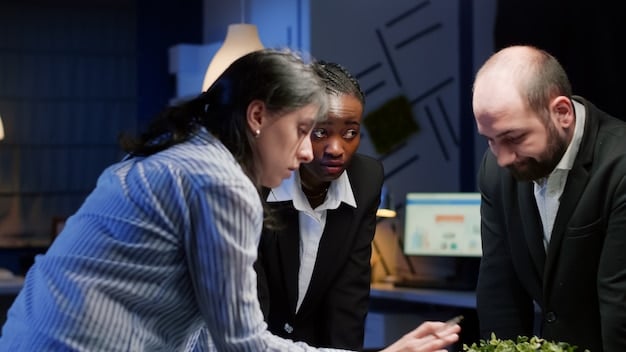 A diverse group of business professionals in a modern office looking at financial projections on a screen, with one person pointing to a chart showing 