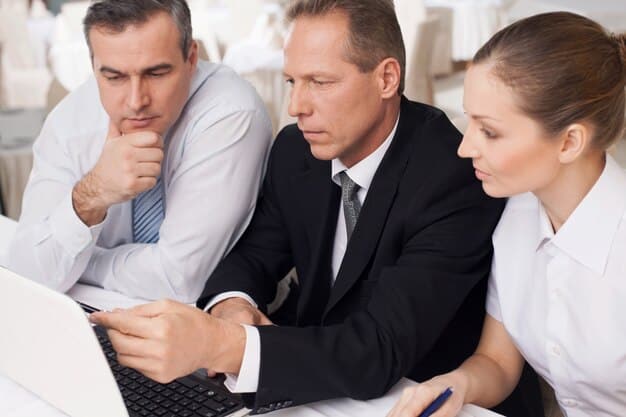 A group of business leaders in a boardroom looking concerned while reviewing economic reports.