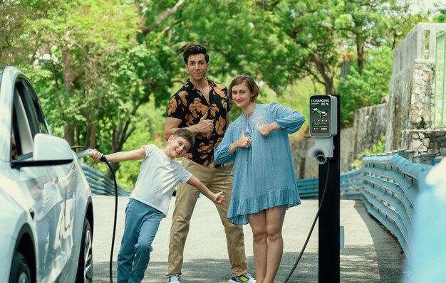 A family or group of friends sharing a ride in an electric car, with charging stations visible in the background, promoting sustainable transportation.