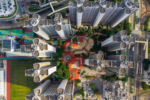 A drone shot capturing a modern urban skyline with several buildings featuring rooftop solar panels, surrounded by green spaces, illustrating integrating renewables in city environments.