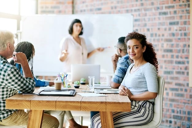 A diverse group of small business employees actively engaged in a training session, with one person presenting on a screen displaying dynamic growth charts, symbolizing effective workforce development and skill enhancement.