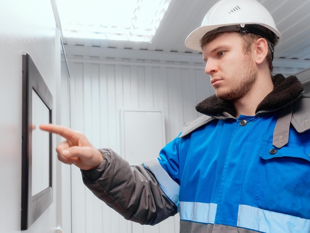 A technician installing a smart thermostat in a commercial building, emphasizing modern energy management.