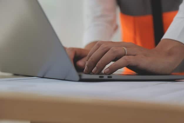 A close-up of a blurred FCC logo on a desk, with a person's hands typing on a laptop in the background, symbolizing regulatory work in progress.